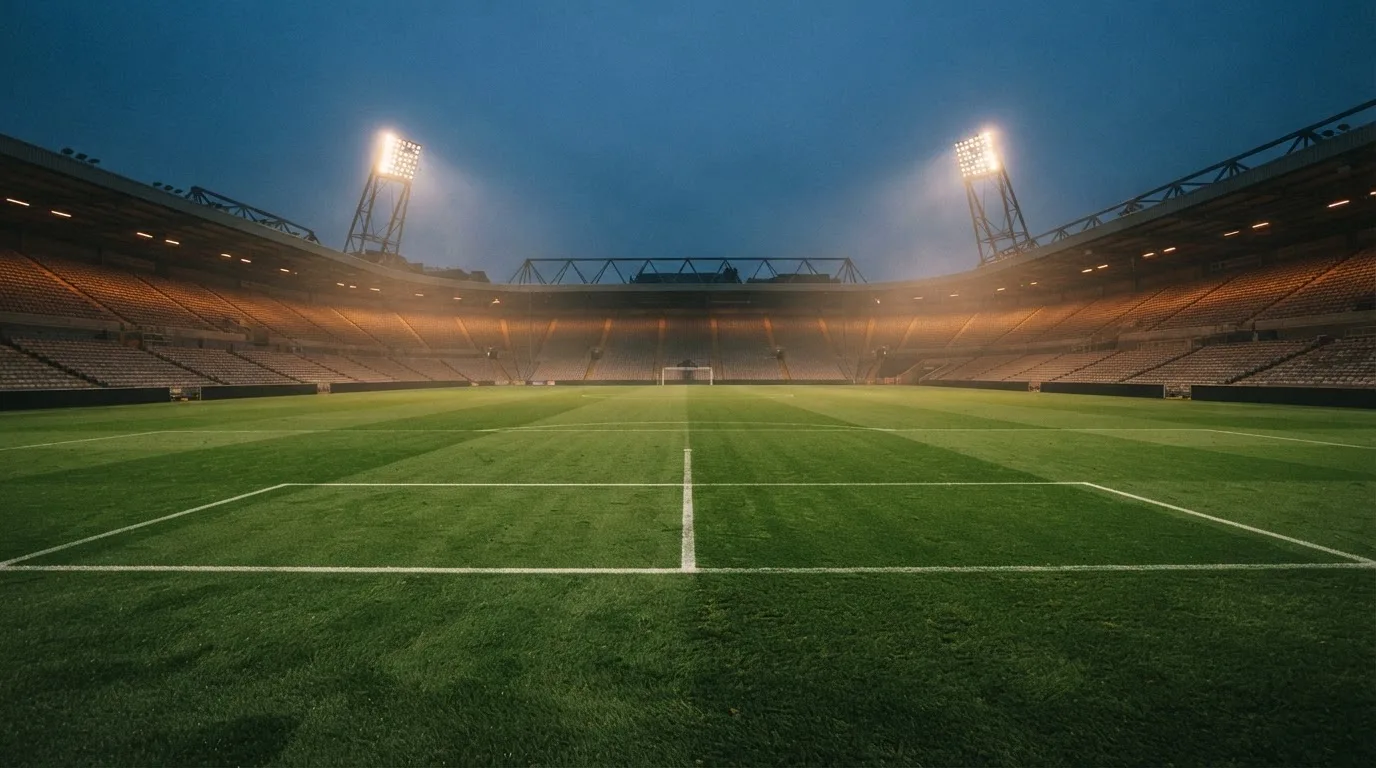 An empty football stadium with floodlight masts at dusk