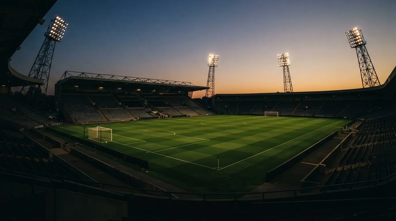 An empty football stadium with floodlight masts at dusk