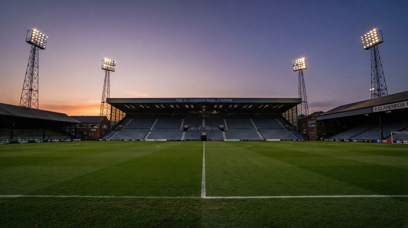 An empty football stadium with floodlight masts at dusk