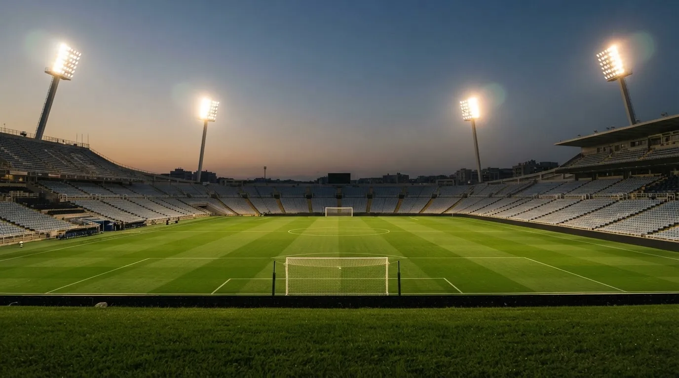 An empty football stadium with floodlight masts at dusk