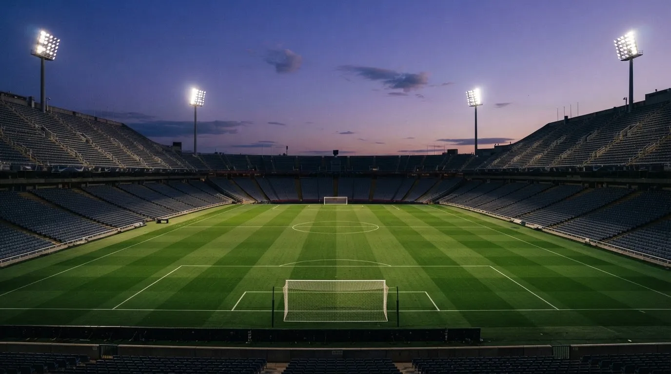An empty football stadium with floodlight masts at dusk