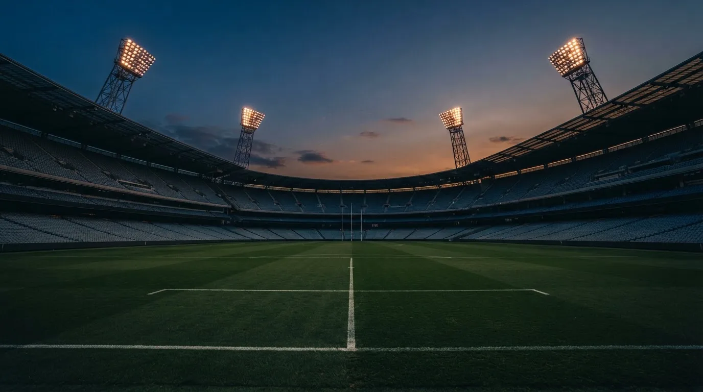 An empty football stadium with floodlight masts at dusk