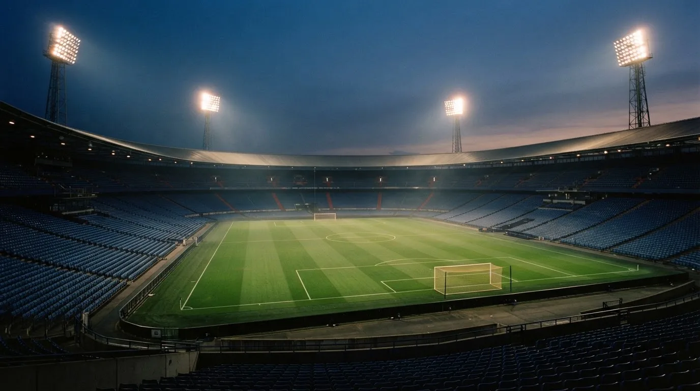 An empty football stadium with floodlight masts at dusk