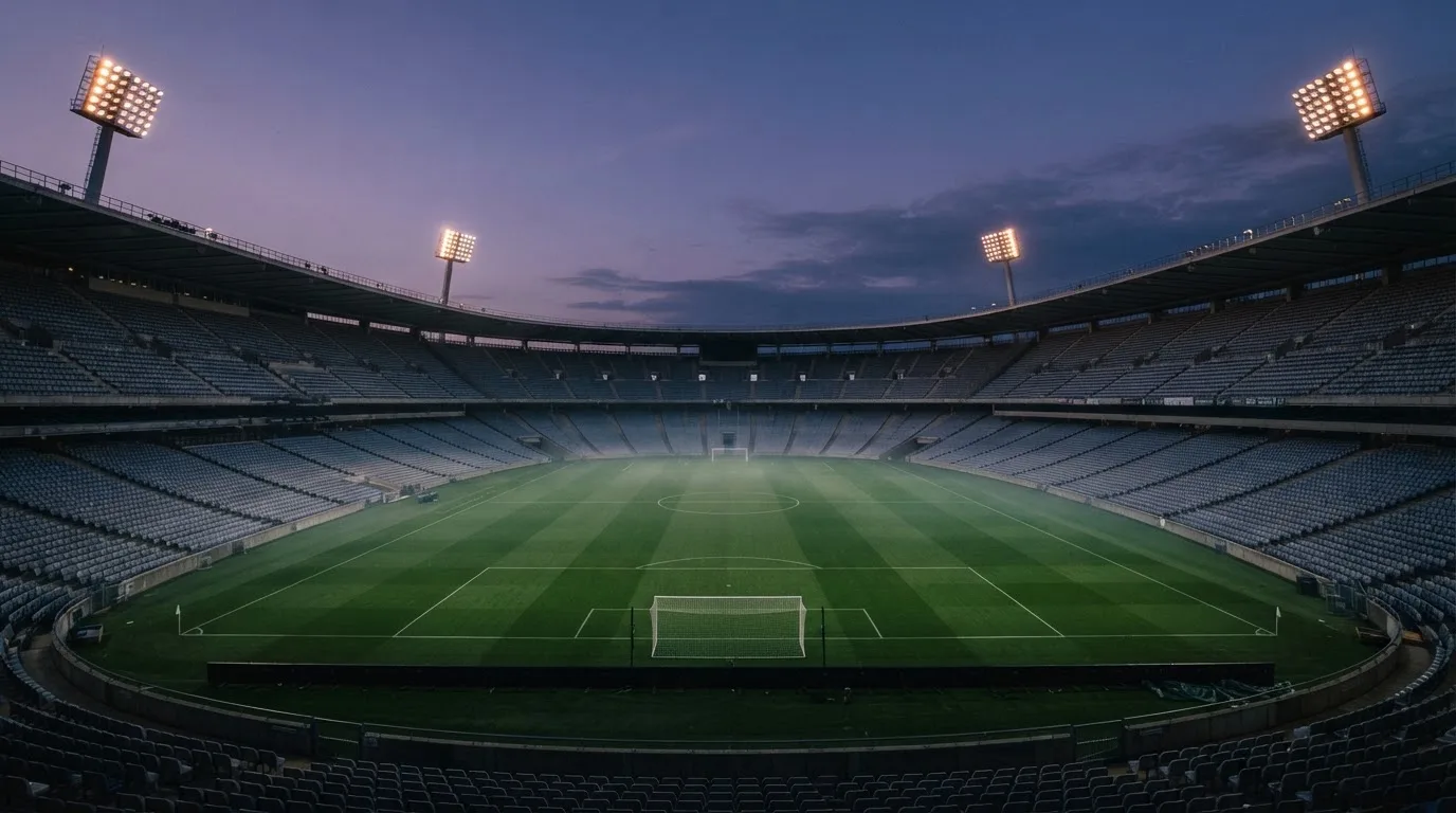 An empty football stadium with floodlight masts at dusk