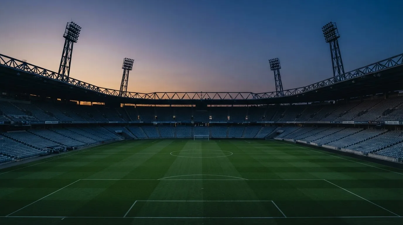 An empty football stadium with floodlight masts at dusk