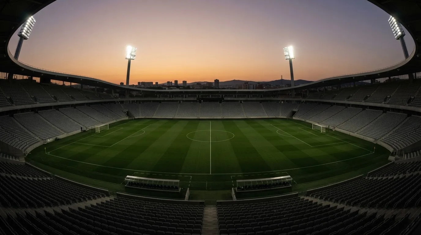 An empty football stadium with floodlight masts at dusk