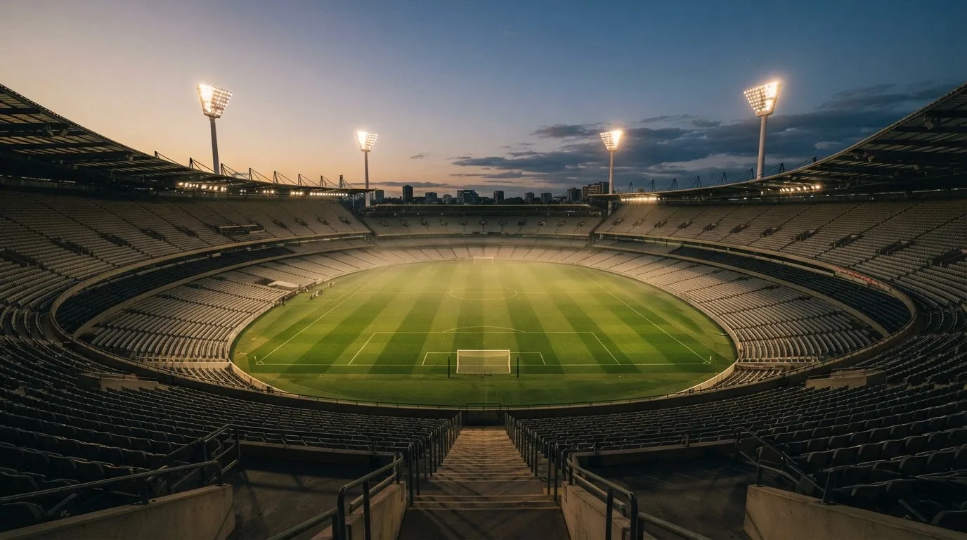 An empty football stadium with floodlight masts at dusk