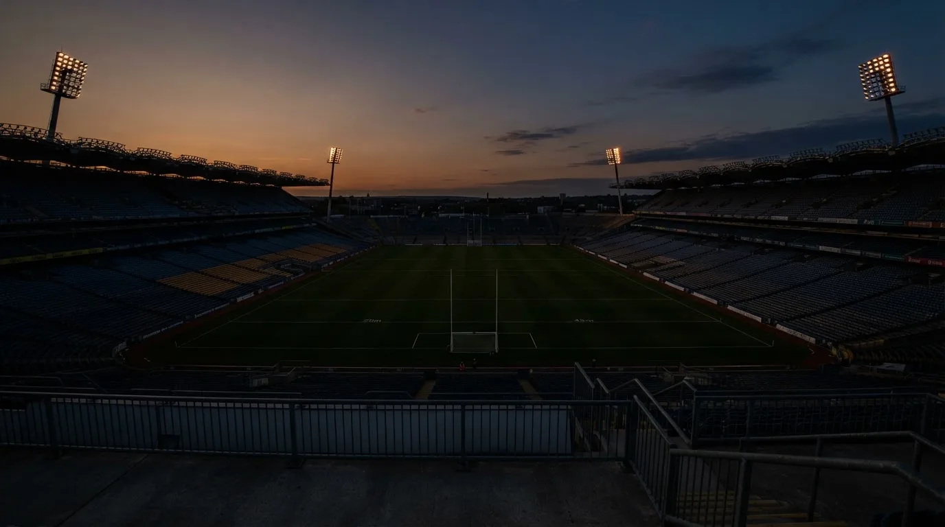 An empty football stadium with floodlight masts at dusk