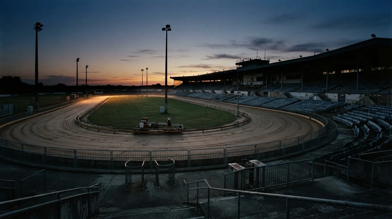 An empty football stadium with floodlight masts at dusk