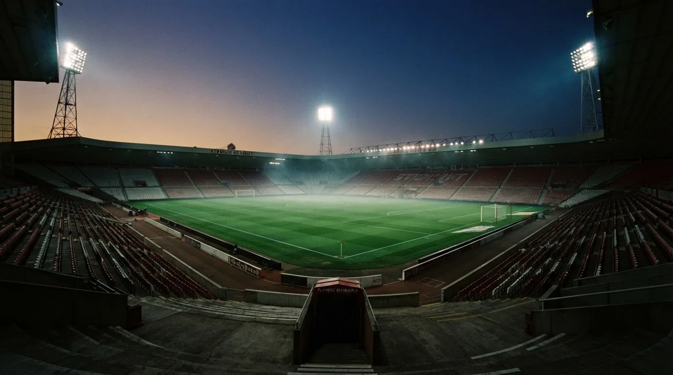 An empty football stadium with floodlight masts at dusk