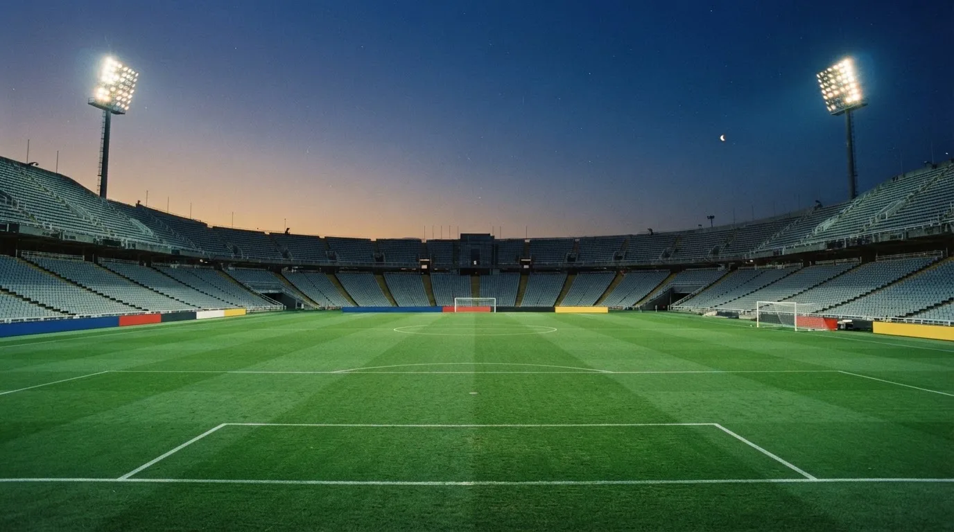 An empty football stadium with floodlight masts at dusk